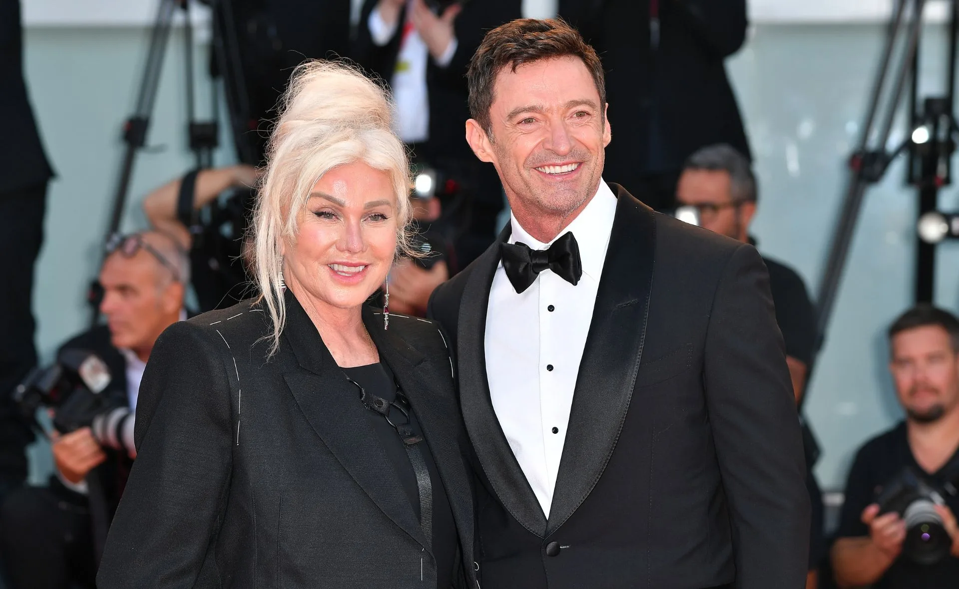 "Two people in formal attire smiling at a red carpet event."