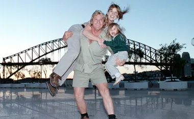 A family poses playfully with a scenic bridge as the backdrop during sunset.