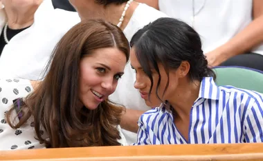 Two women engaged in conversation, sitting close together, one in stripes, other with patterned attire.