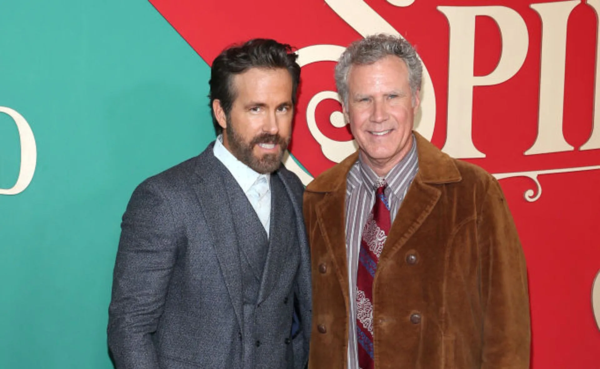 Two actors posing together at a "Spirited" event with a colorful backdrop.