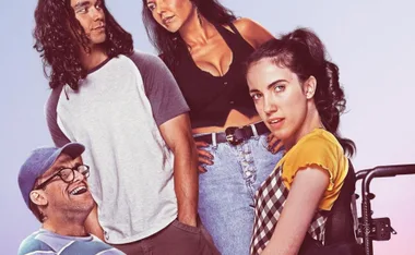 A group of four diverse individuals, with one person seated in a wheelchair, pose against a light background.