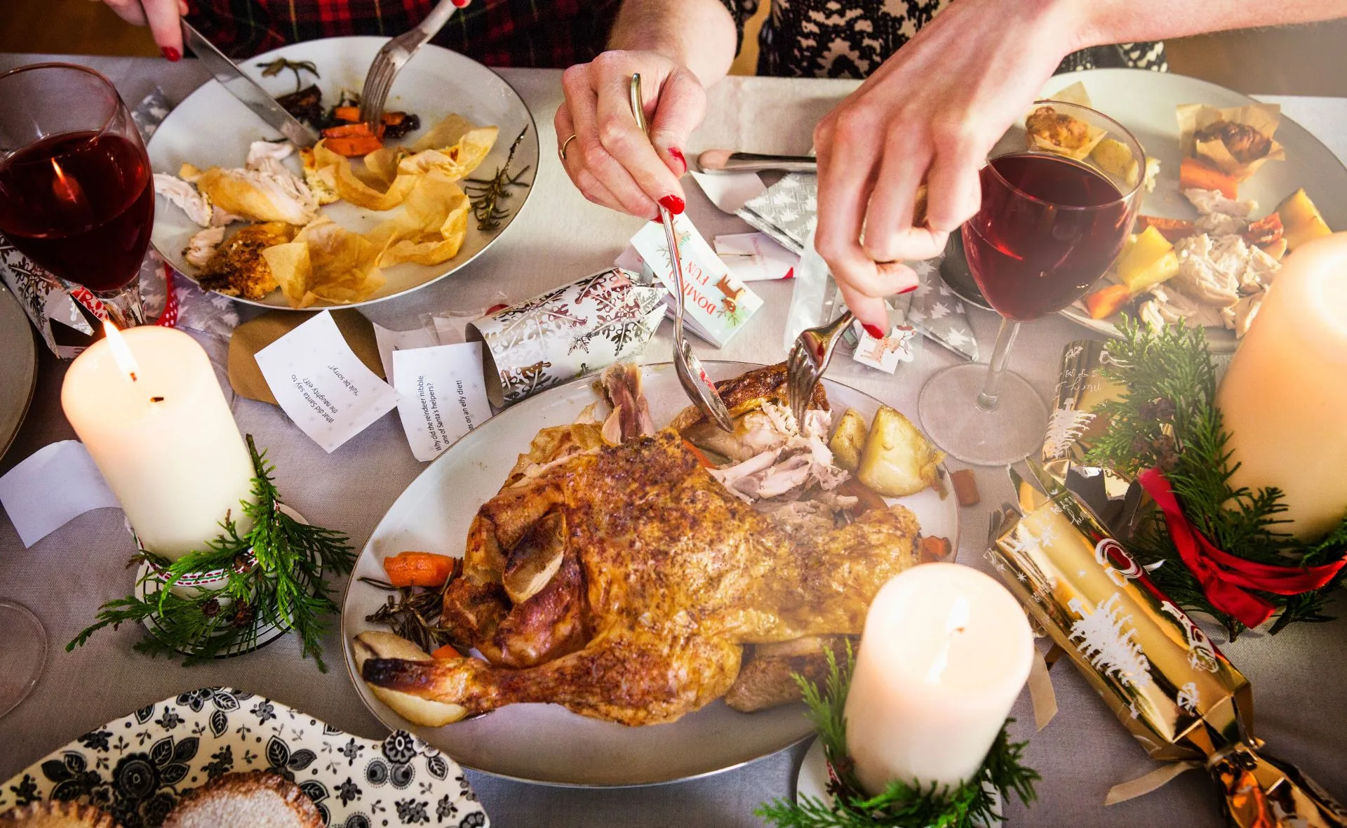 Christmas table setting with roast turkey, candles, wine, and holiday decorations.
