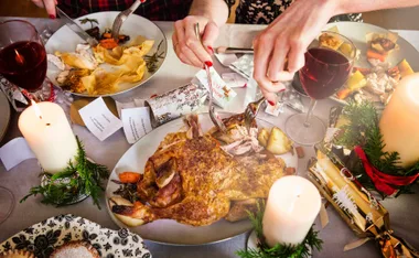 Christmas table setting with roast turkey, candles, wine, and holiday decorations.