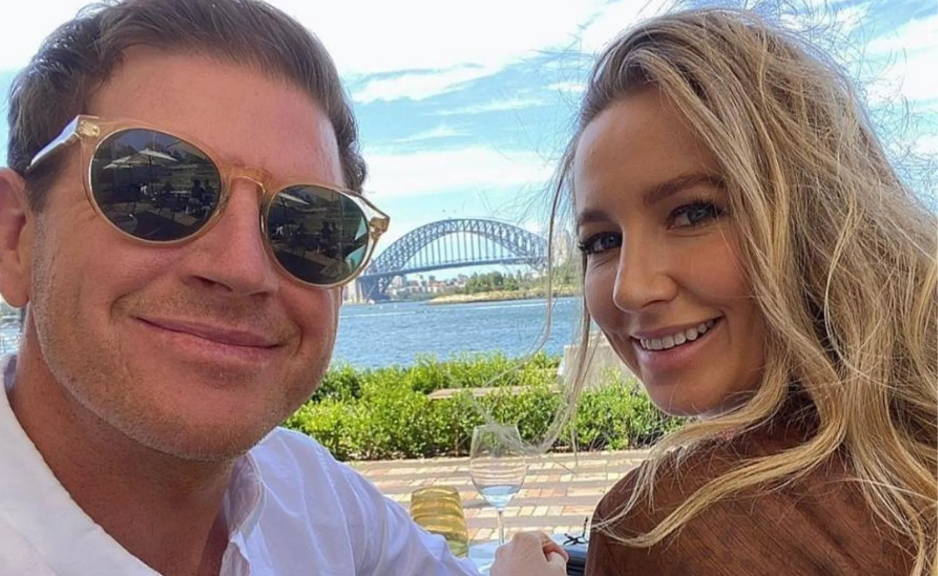Couple smiling with Sydney Harbour Bridge in background on a sunny day.