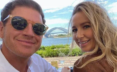 Couple smiling with Sydney Harbour Bridge in background on a sunny day.