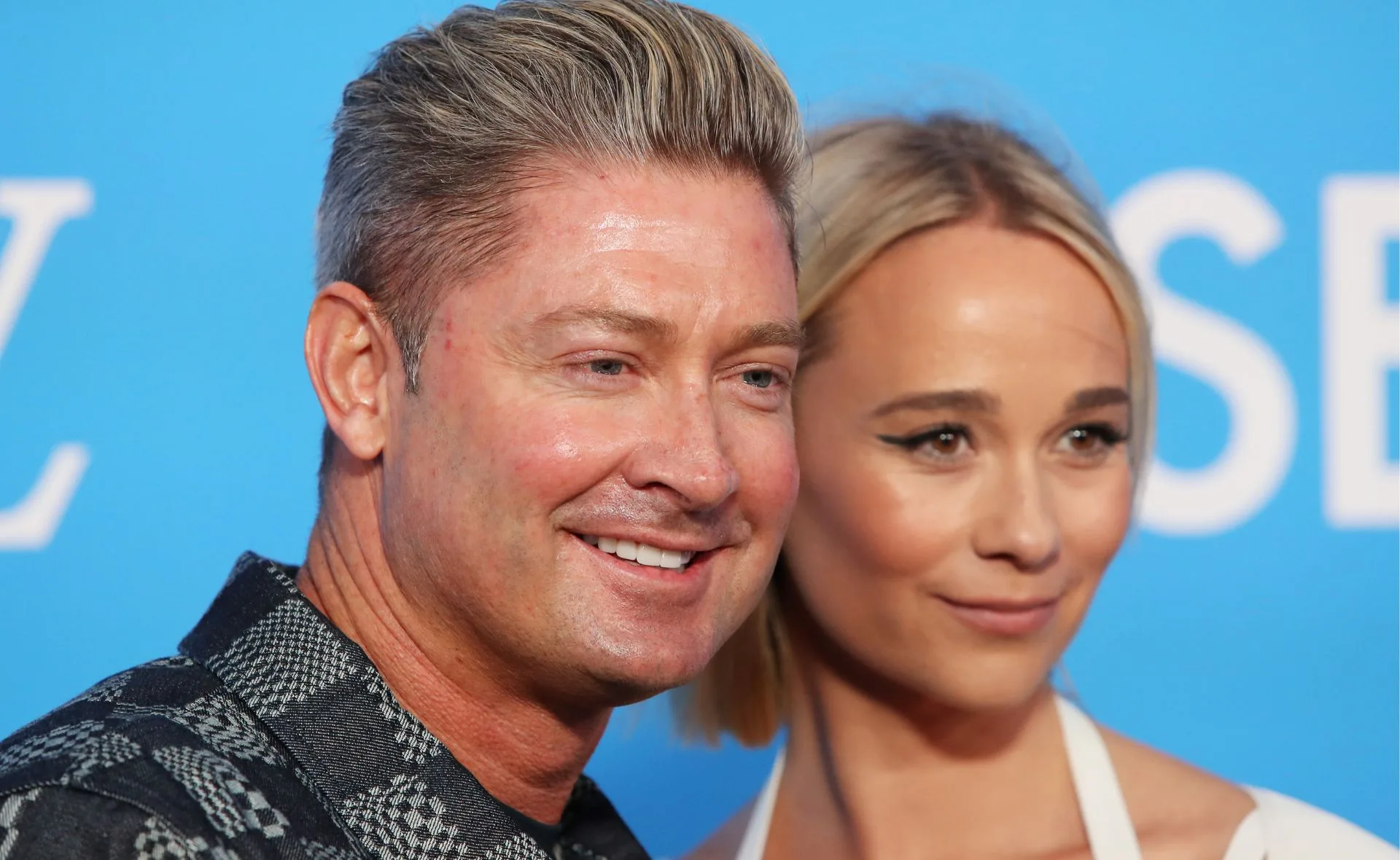 Two people smiling at an event with a blue background.