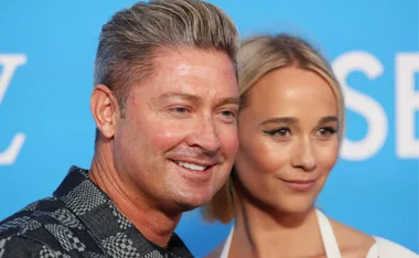 Two people smiling at an event with a blue background.