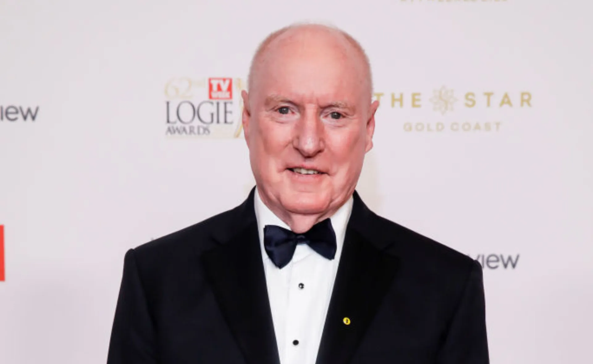 Man in a tuxedo with a bowtie at a Logie Awards event, smiling at the camera.