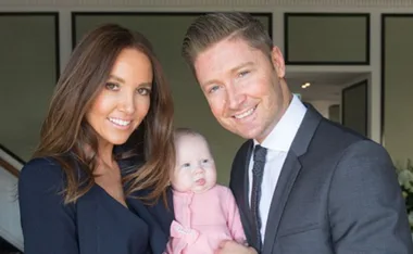 A couple smiling while holding their baby in a formal setting.