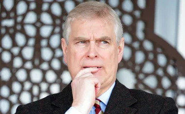 A man looking thoughtful, wearing a suit with a patterned background.
