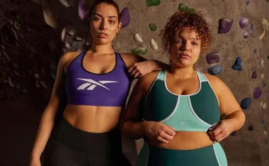 Two women in Reebok activewear posing in front of a climbing wall.