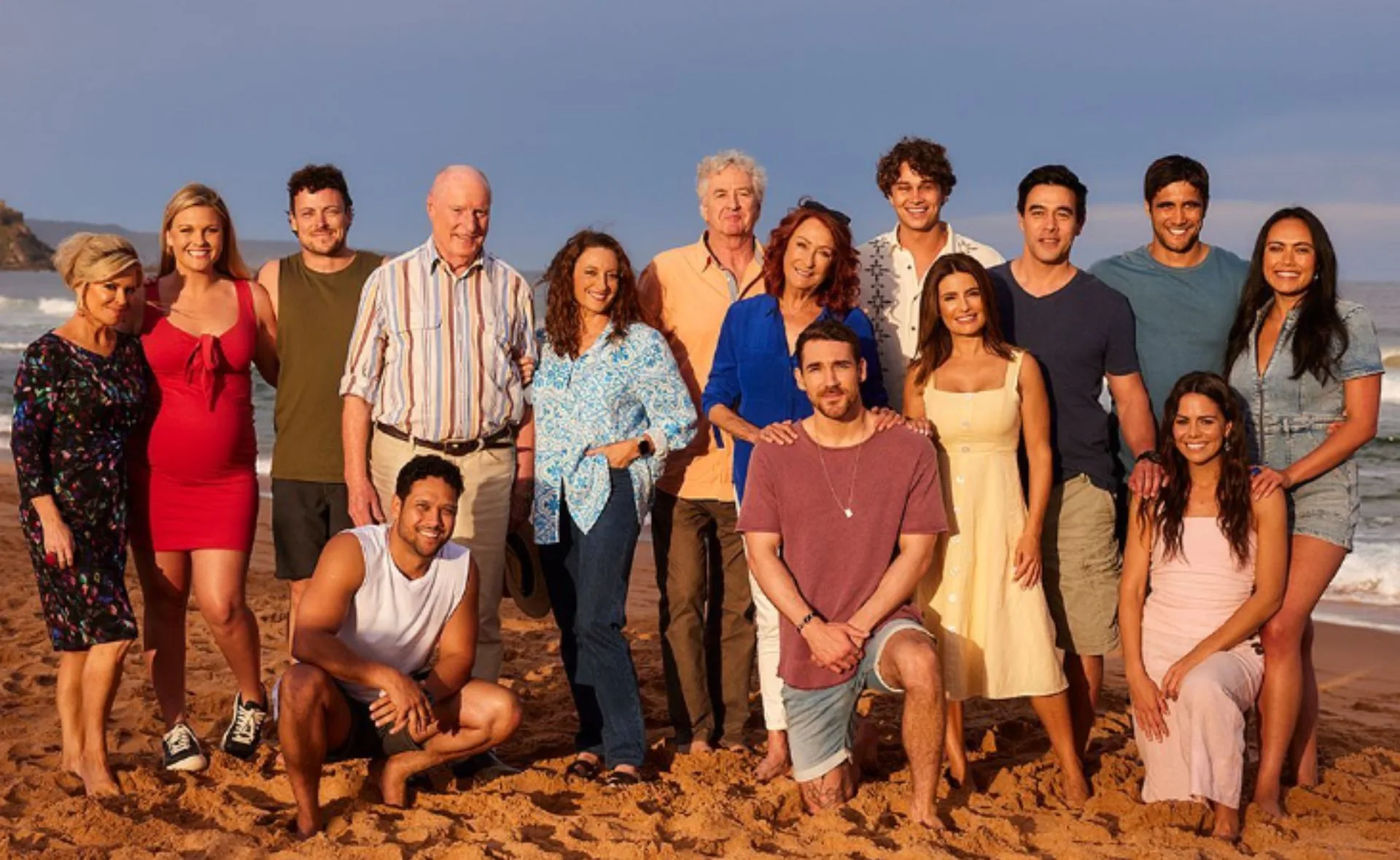 A group of "Home and Away" cast members reunited, posing together on a sandy beach.
