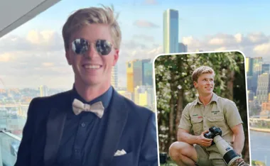 Robert Irwin smiling in a suit with city skyline; inset shows him in khaki outfit holding camera in a park.