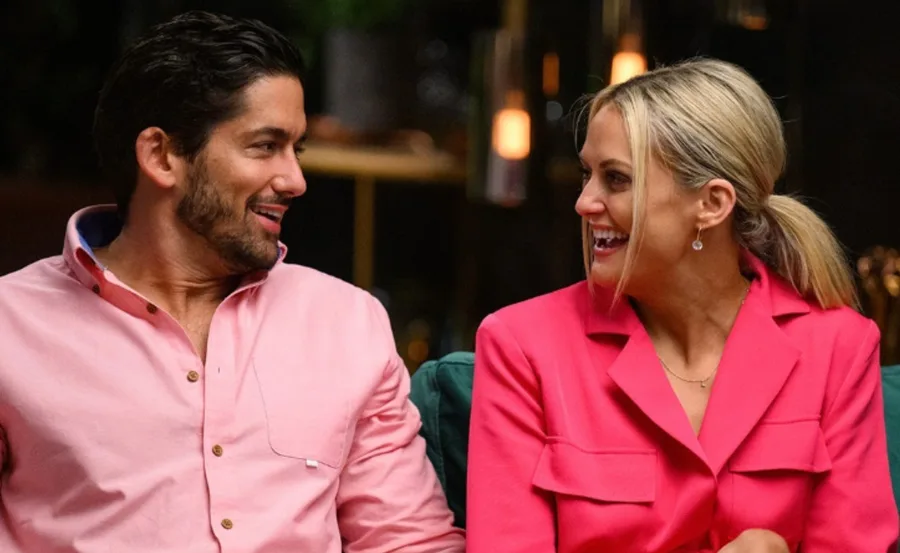 A couple from "Married at First Sight" smiling at each other, wearing pink outfits.