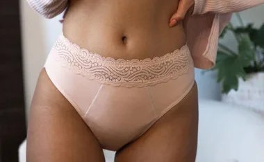 High-waisted pastel pink underwear with lace detail, worn by a model.