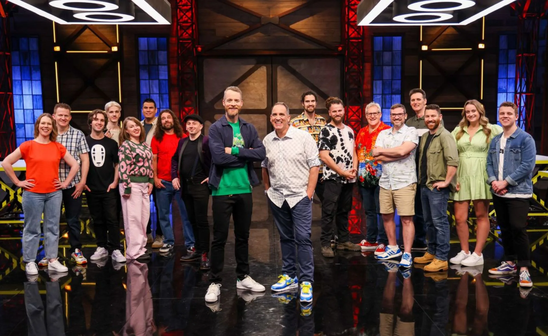 Cast of Lego Masters Australia 2023, featuring contestants and hosts, posed on a stage with colorful lighting.