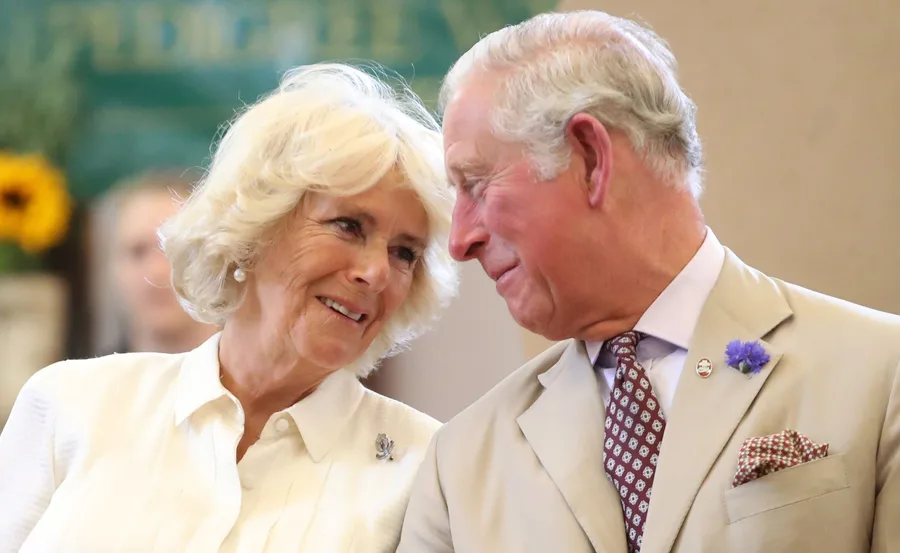 Older couple smiling at each other, wearing formal attire, with blurred background.