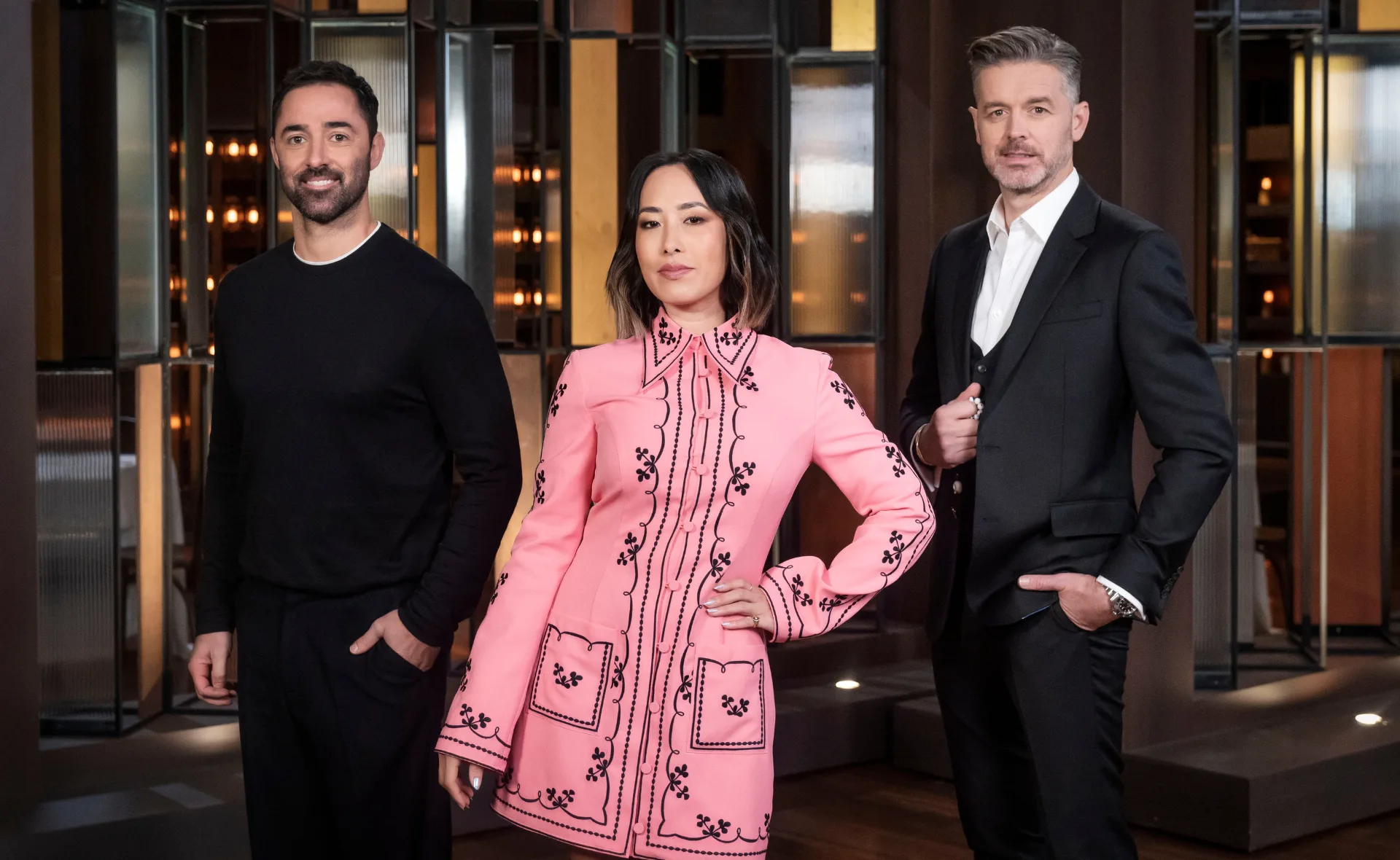 Three people posing confidently in stylish outfits against a modern interior backdrop.