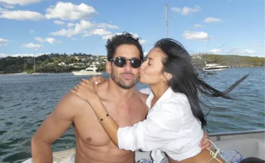 Man and woman embracing on a boat; woman kisses him on the cheek.