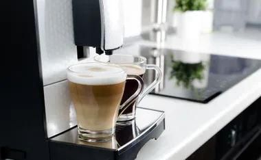 Coffee machine brewing two cups on a modern kitchen counter.