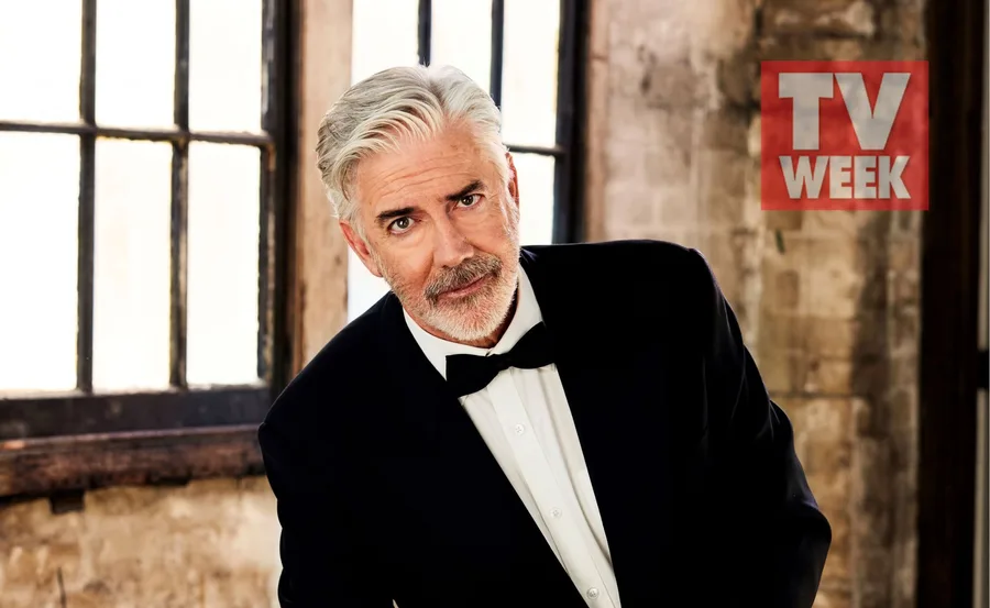 A man with silver hair and a beard in a tuxedo poses indoors with a "TV WEEK" logo in the background.