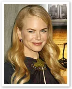 Portrait of a smiling woman with long blonde hair at an event, wearing a dark outfit with a decorative brooch.