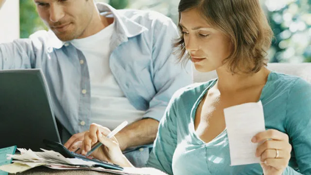 Couple reviewing finances together; woman with receipt, man on laptop.