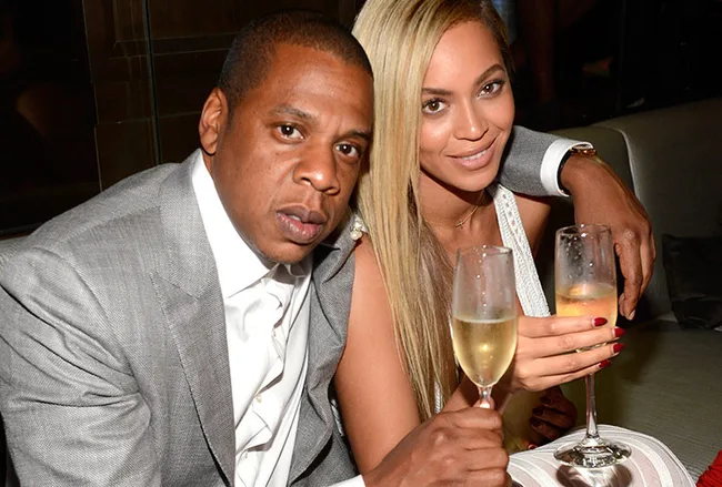 A couple in formal attire holding champagne glasses, smiling at the camera.