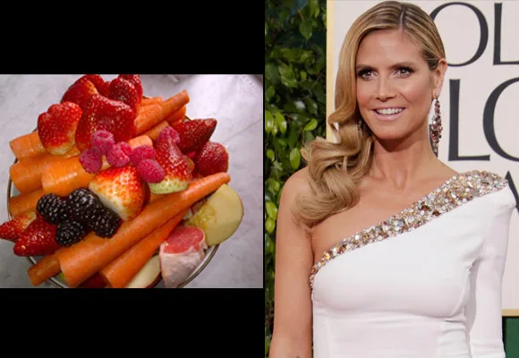 Fruit and veggie bowl next to a person in a white dress at an event.
