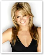 Blonde woman smiling in a black top, standing against a white background.