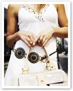 Woman in white dress holding a handbag with ornate belt detail.