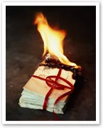 A stack of letters tied with a red ribbon is burning from the top.