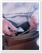 Person taking a few bills from a wallet into a brown handbag.