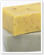 Two bars of soap, one yellow with speckles on top of a plain green bar, both stacked vertically.