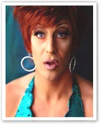 Person with short red hair, large hoop earrings, and a teal sequined top looking forward with a surprised expression.