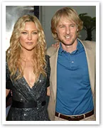 Two people posing together at an event, one in a sparkly dress and the other in a suit with a blue shirt.