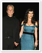 A couple holding hands, the woman in a blue dress and the man in a black suit, walking at an event.