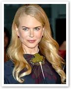Blonde woman with long hair wearing a dark dress and necklace, looking to the side, at a formal event.