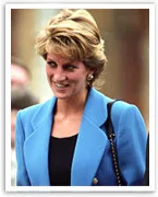 Smiling woman in a blue blazer with short hair, wearing earrings, and a black top.