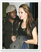 Two people walking together, the person on the right holding a coat, the other wearing a cap, both engaged in conversation.