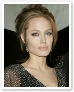 A woman in a black, sparkling dress with an updo hairstyle poses at an event.