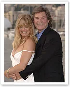 Couple smiling and embracing in a scenic outdoor setting, dressed in formal attire.