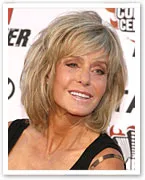 Farrah Fawcett smiling at an event, with a short, layered hairstyle and a radiant expression.