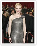 A person in an elegant, sparkling one-shoulder gown at a formal event, with a crowd in the background.