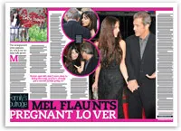 Mel Gibson walks on a red carpet with a woman in a black dress. They are holding hands and smiling at each other.