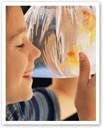 A child smiling while holding a bag with two goldfish inside.