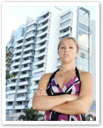 Woman standing confidently with arms crossed in front of a modern high-rise building.