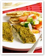 Grilled fish with herbs, served with sliced tomatoes, cucumber salad, and crispy bread on a white plate.