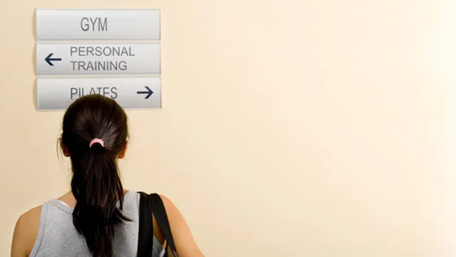 Woman looking at signs for gym, personal training, and pilates directions.