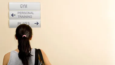 Woman looking at signs for gym, personal training, and pilates directions.